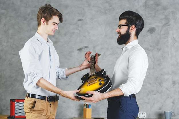 Uomini d'affari attraenti che giocano con la chitarra