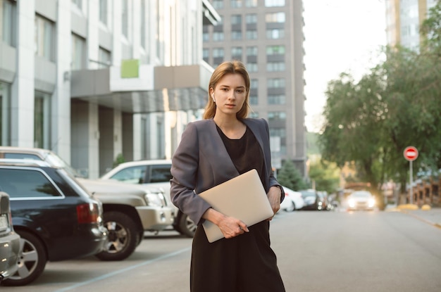 그녀의 컴퓨터와 함께 주차장 근처 카메라를보고 매력적인 사업가