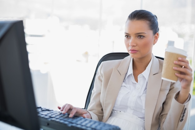 Attractive businesswoman holding coffee while working