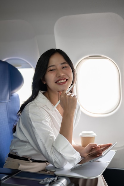 An attractive businesswoman is sitting in the window seat on a plane traveling for a business trip