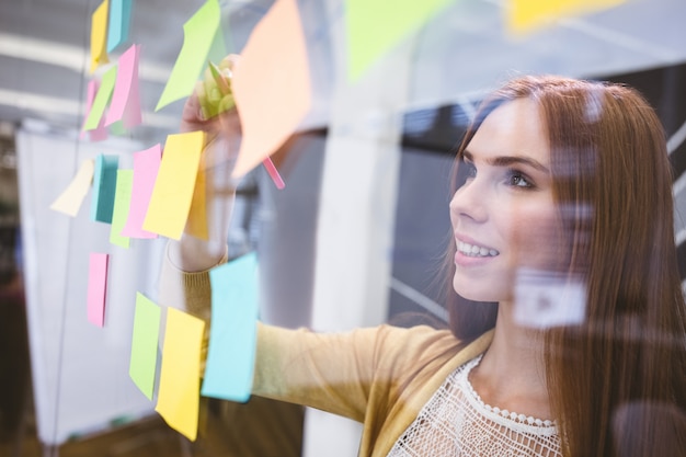 Attractive businesswoman writing on sticky notes