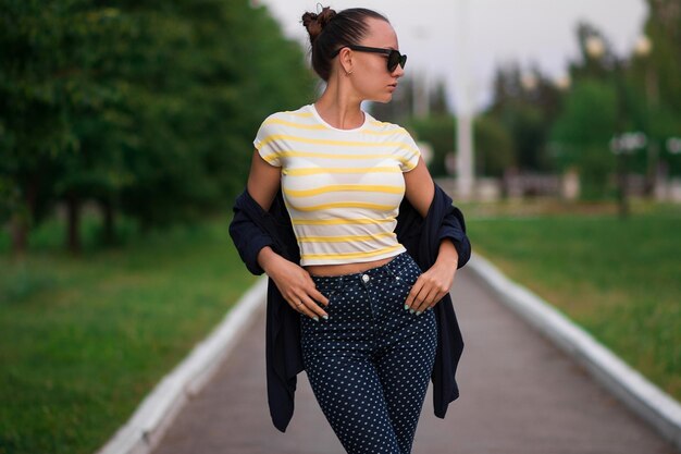 Attractive calm slim female in yellow and white striped shirt and blue with white polka dots pants