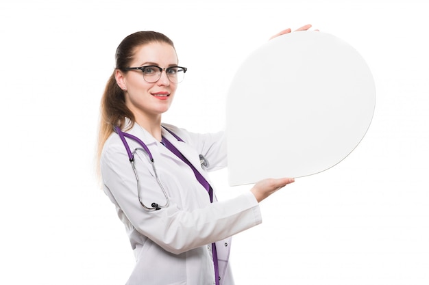 Attractive caucasian brunette female doctor standing in office smiling with speech bubble in her hands