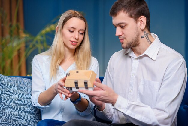 Attractive caucasian man and woman discussing design of the model of 3d maket of house.