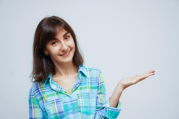 Attractive Caucasian woman open hands palm up holding something on isolated gray background