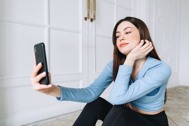 Привлекательная кавказская женщина с помощью мобильного телефона после фитнеса дома.