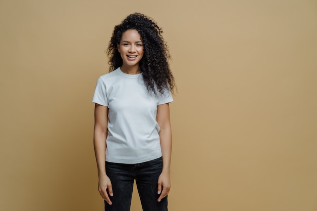 Attractive cheerful woman with Afro hairstyle smiles positively