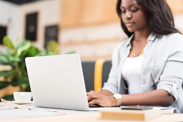 Attractive concentrated african american woman using laptop in cafe