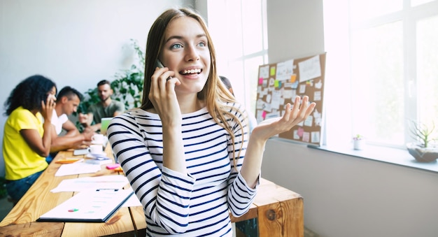 Attractive confident modern business woman in casual clothes looks at the camera and smiling. Modern start-up business team. Co-workers or students