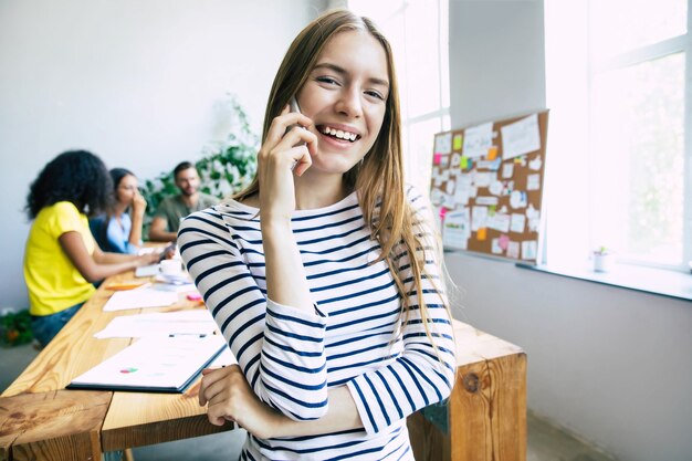 Attractive confident modern business woman in casual clothes looks at the camera and smiling. Modern start-up business team. Co-workers or students