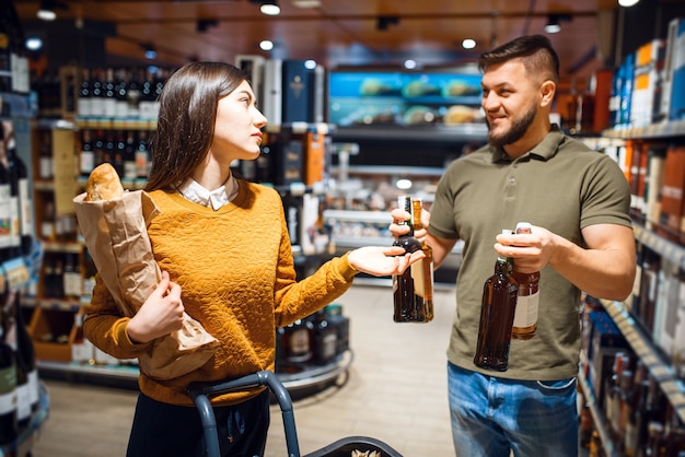 Attractive couple choosing alcohol in grocery supermarket