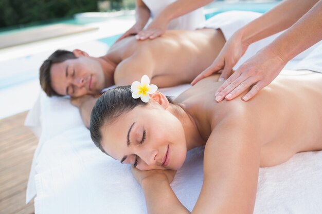 Attractive couple enjoying couples massage poolside