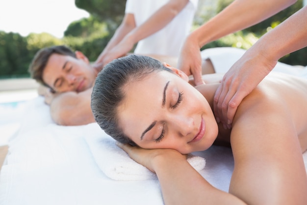 Attractive couple enjoying couples massage poolside