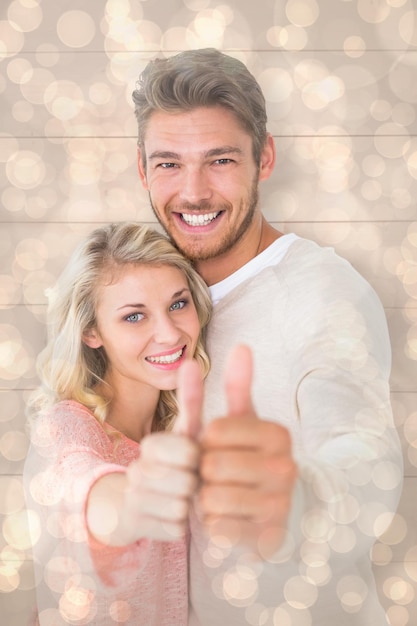 Attractive couple showing thumbs up to camera against light glowing dots design pattern