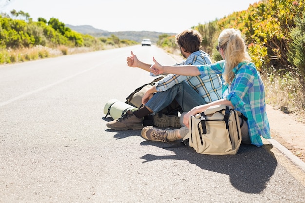 Attractive couple sitting on the road hitch hiking