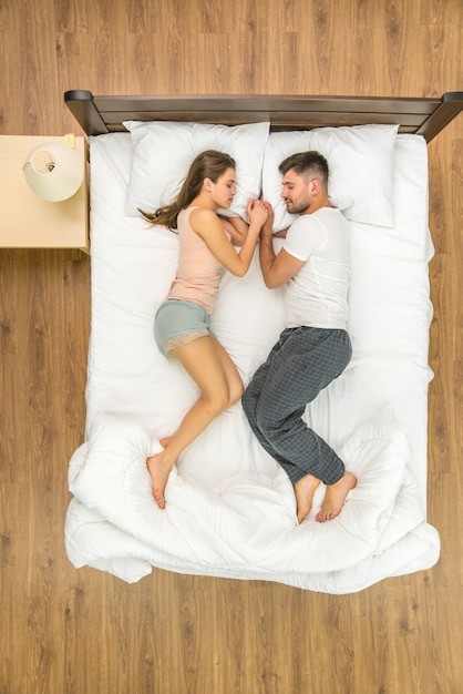 The attractive couple sleeping on the bed. View from above