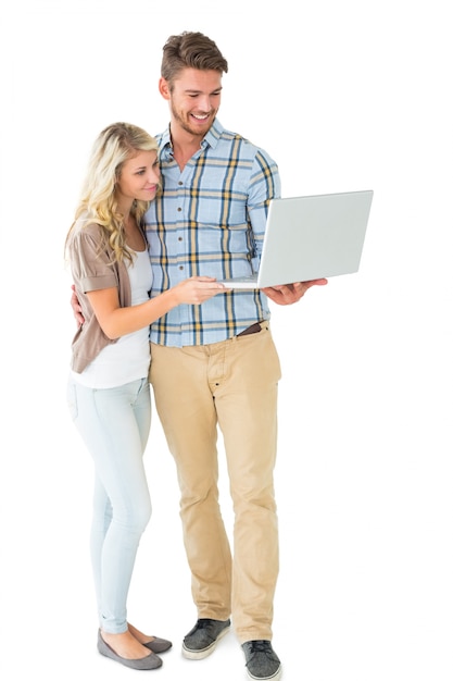 Attractive couple standing and using laptop