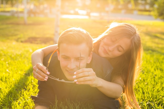 Attractive couple of teenagers lying in the grass smiling and have fun.