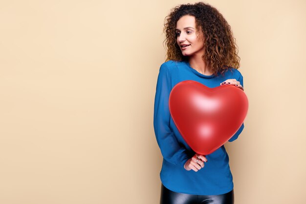 Attractive curly hair woman holding red heart shape balloon