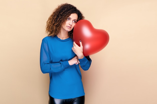 Attractive curly hair woman holding red heart shape balloon