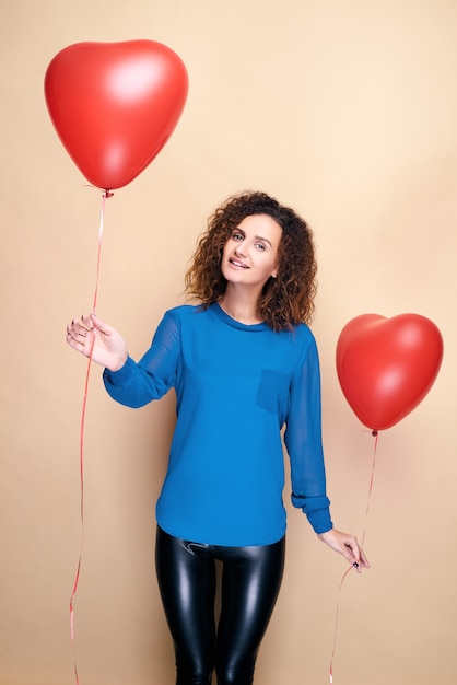 Attractive curly hair woman holding red heart shape balloon