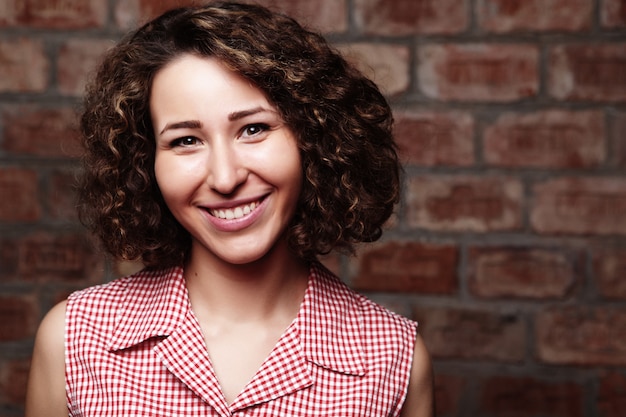 Attractive curly woman on brick wall