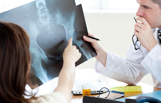 Attractive doctor analyzing an xray with a female patient