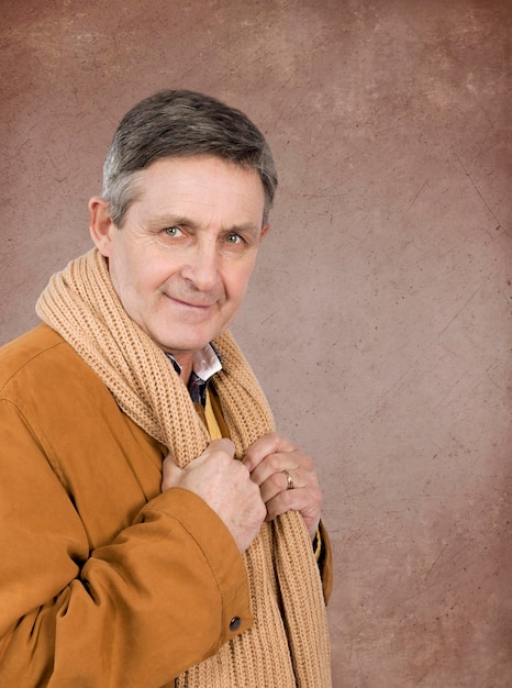 Attractive elderly man elegantly dressed in sweater jacket and scarf