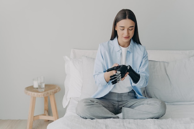 Attractive european girl adjusting her cyber arm at home Artificial hand and arm with wrist joint