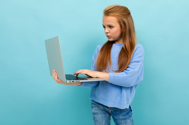 Привлекательная европейская девушка печатает на ноутбуке на голубом