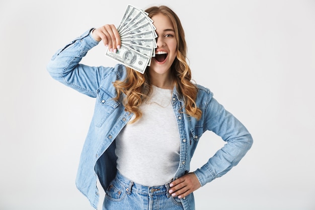 Attractive excited young girl standing isolated over white , showing money banknotes