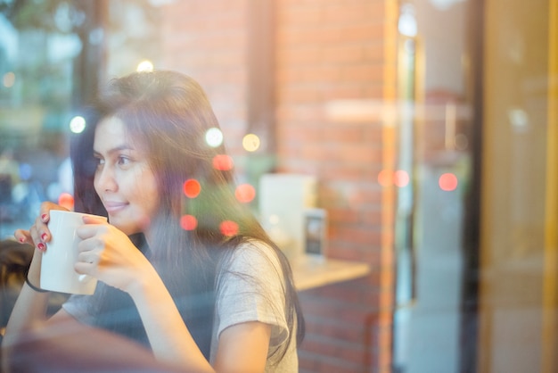 コーヒーショップでコーヒーを飲む魅力的な女性アジアの大学生