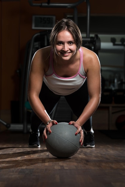 Attractive Female Athlete Performing PushUps On Medicine Ball