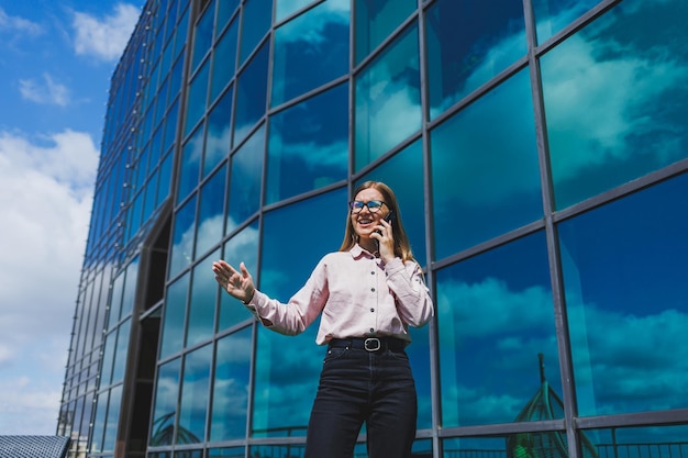 Attractive female blogger holding a modern gadget in her hands looking thoughtful and daydreaming young blogger holding a mobile phone thinking about an idea for posting on social media