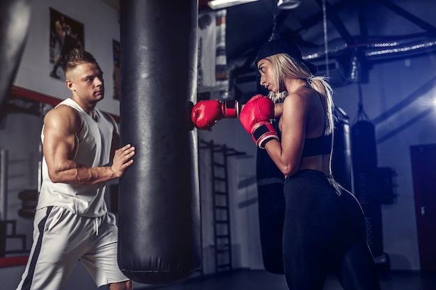 Attraente pugile femminile che si allena colpendo il sacco da boxe