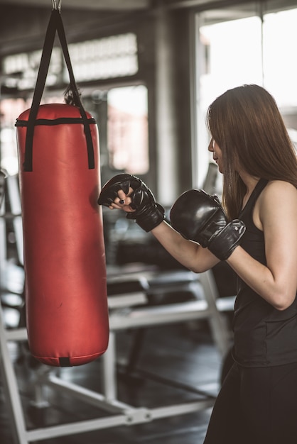 Foto addestramento femminile attraente del pugile con kick boxing alla palestra con i guanti neri.