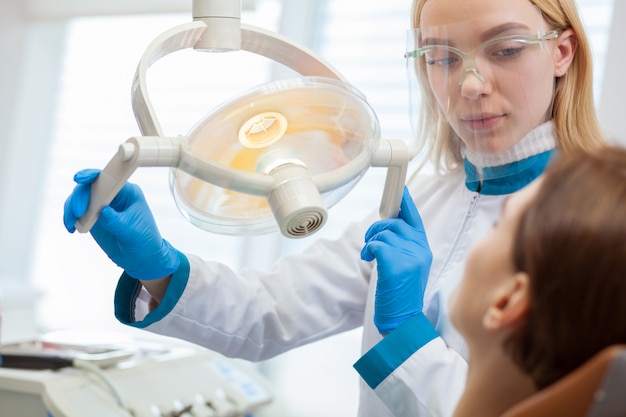 Attractive female dentist examining teeth of female patient