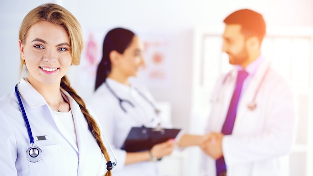 Attractive female doctor in front of medical group, medical staff checking medical records on background