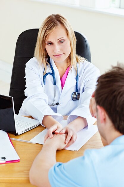 Attractive female doctor hanging the hand of her male patient 