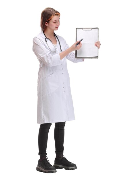 Attractive female doctor in a lab coat displaying a blank clipboard in front of her chest and pointing to it with a pen