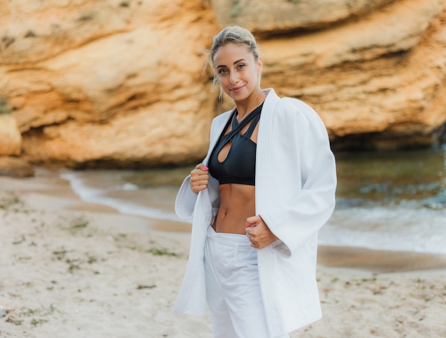 Attractive female martial artist in a white kimono  on wild beach