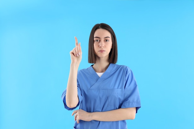 Attractive female trainee nurse on blue background