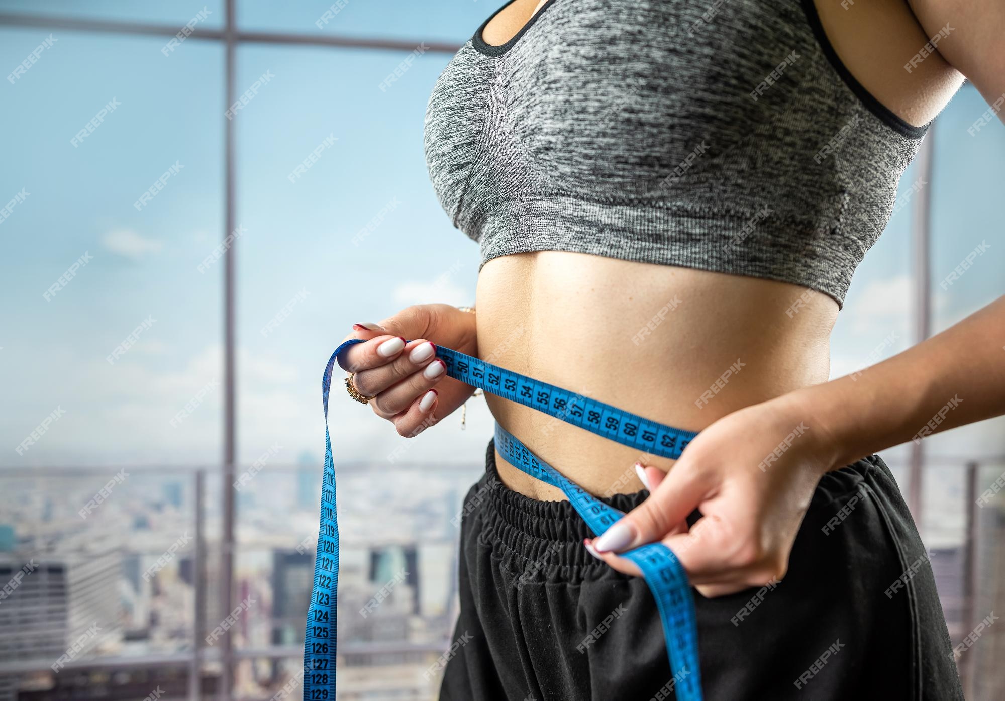 Premium Photo  Attractive female trainer holds measuring tape for body  measurement isolated on a typical background healthy lifestyle concept