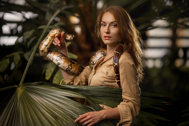 Attractive female zookeeper with python snake in tropical nature