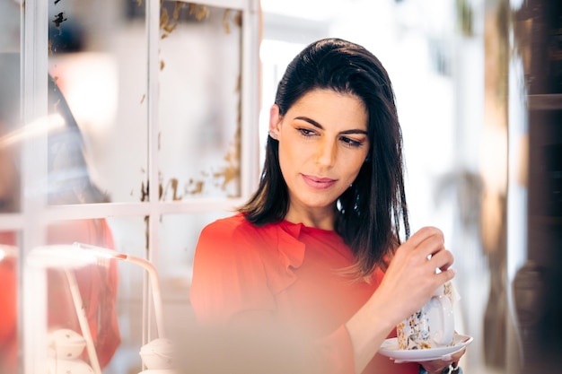 魅力的でフェミニンな女性はリラックスしてコーヒーを飲む