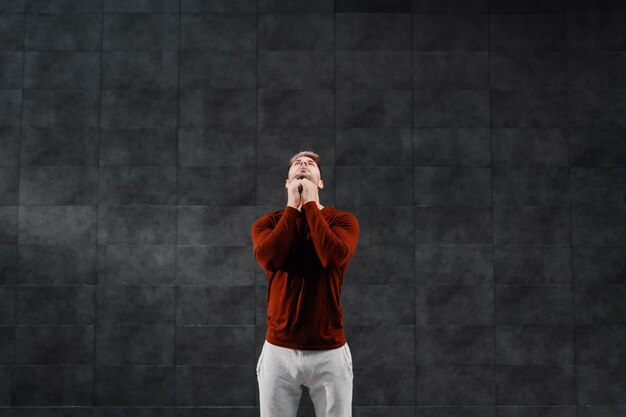 Attractive fit caucasian breaded sportsman in tracksuit doing warm up exercises for neck before running. 