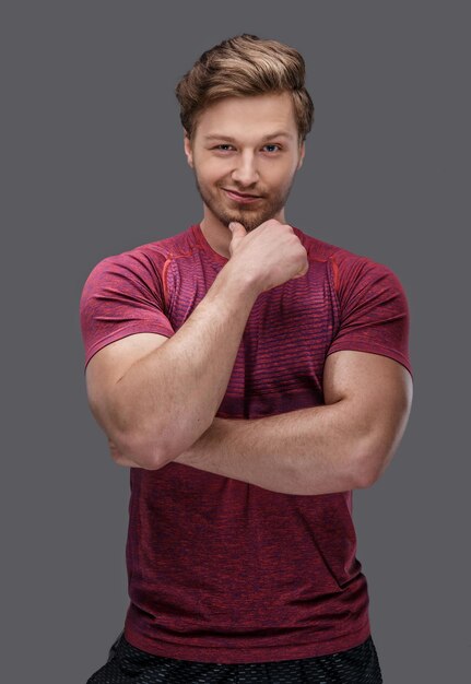 Attractive fit guy in a red t shirt isolated on a grey background.