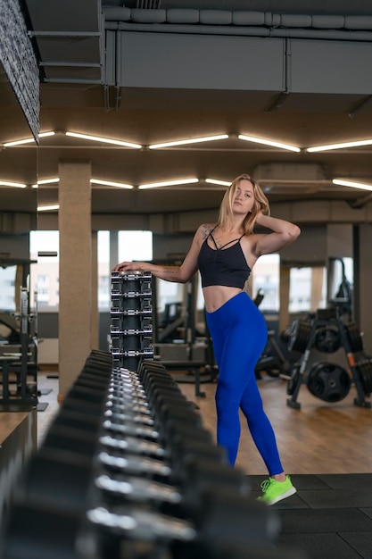 Привлекательная подтянутая женщина с идеальным телом носит спортивную одежду для тренировок в тренажерном зале Девушка позирует для фото Спортивное снаряжение