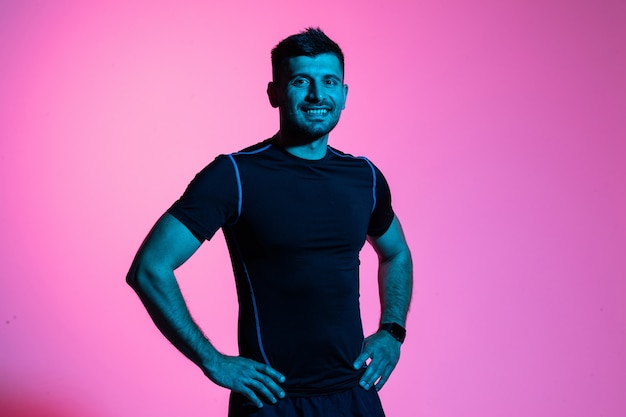 Attractive fitness man in sportswear isolated on pink light background