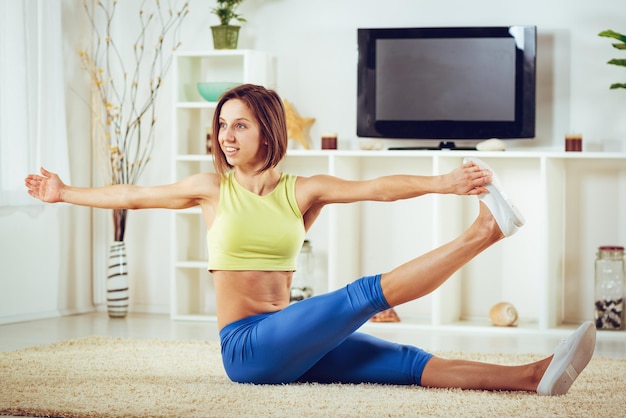 Attractive fitness woman doing exercises and stretching in her living room.